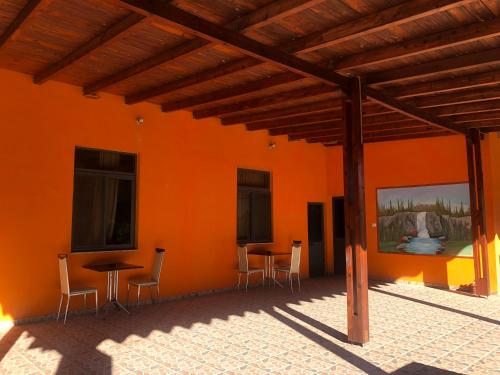 an orange wall with tables and chairs in a patio at Hotel Xhej in Rubik