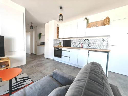 un salon avec un canapé et une cuisine dans l'établissement Agréable appartement lumineux avec grande terrasse, à La Rochelle