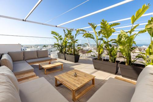 a rooftop patio with a couch and tables and plants at Pure Formosa Concept Hotel in Olhão
