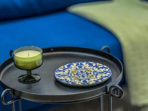 a candle and a plate and a glass on a tray at Le Bleuet Tout confort in La Soukra