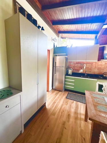 a kitchen with white cabinets and a wooden floor at RECANTO DOS PASSARINHOS LINDA CASA COM 2 quartos in Balneário Camboriú