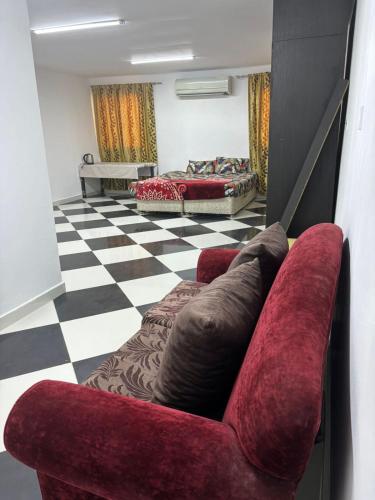 a living room with a red couch and a checkered floor at LARGE M BEDROOM Attached Bathroom with Terrace Access in a villa Sharjah in Sharjah