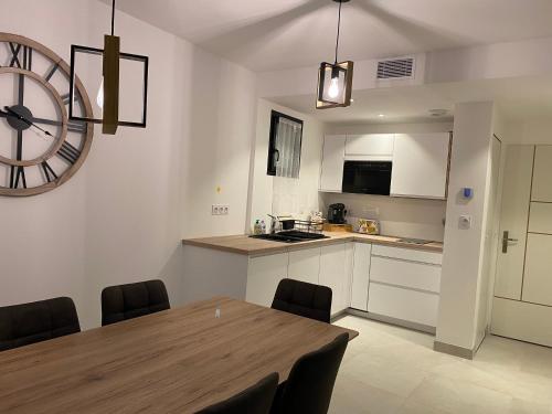 une cuisine avec une table et une grande horloge murale dans l'établissement La Maison Blanche, à Bouguenais