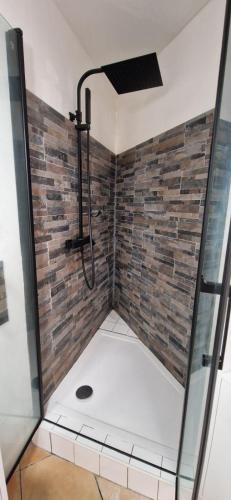 La salle de bains est pourvue d'une douche et d'un mur en briques. dans l'établissement Charmante Maisonnette, Piscine, Jardin, Parking, à Argelès-sur-Mer