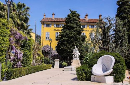 un bâtiment jaune avec une statue dans un jardin dans l'établissement Appartement 2 pièces cosy, à Grasse