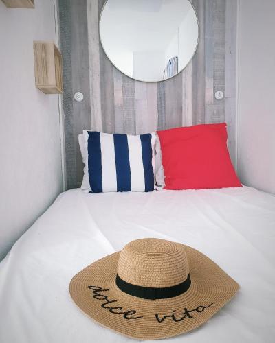 un chapeau de paille posé sur un lit avec un oreiller rouge dans l'établissement Studio front de mer, à Merville-Franceville-Plage