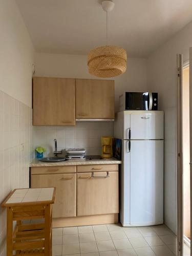 eine Küche mit einem weißen Kühlschrank und einem Tisch in der Unterkunft Charmant Studio de 28 M2 in Brando