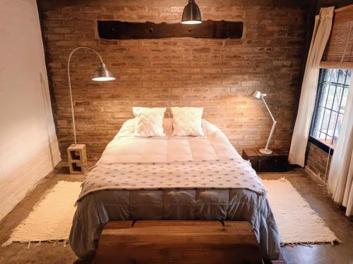 a bedroom with a bed and a brick wall at Casa Darragueira de Chacras de Coria in Chacras de Coria