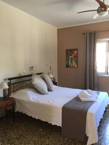 a bedroom with a bed with white sheets and a window at Villa Lucia in Lixouri