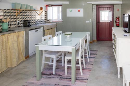 a kitchen with a white table and white chairs at Casas Velhas - Casa da Taberna in Castro Verde