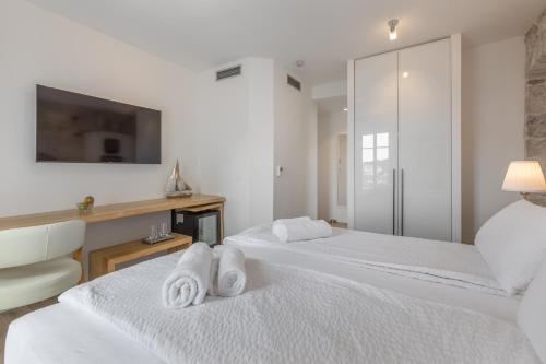 two white beds in a room with a tv at Casa Columba - 4 Star Design Boutique Hotel with Outdoor Pool & Private Garden in Makarska