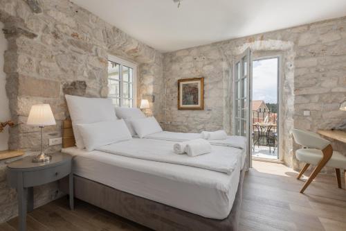 a bedroom with a king sized bed with a stone wall at Casa Columba - 4 Star Design Boutique Hotel with Outdoor Pool & Private Garden in Makarska