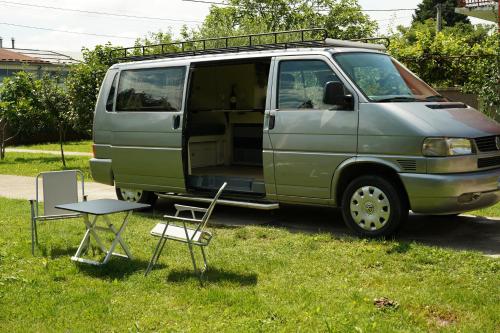 a green van parked in the grass with a table and chairs at Montenegro Camper VOYAGER in Podgorica