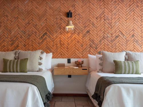 a room with two beds and a wooden wall at La Paranera Hotel & Relax in Comala
