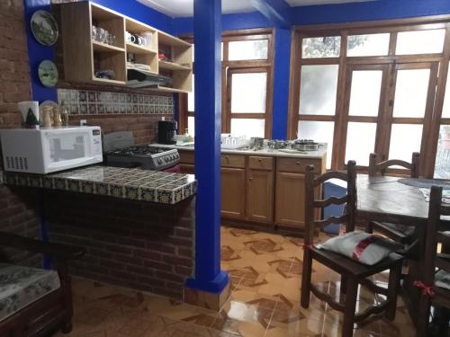 a kitchen with blue walls and a table with a microwave at COYOACAN DEPARTAMENTO TIPO COLONIAL in Mexico City