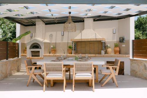 an outdoor kitchen with a table and chairs at Emerald Harmony Villa with Private Pool & Jacuzzi in Skouloúfia