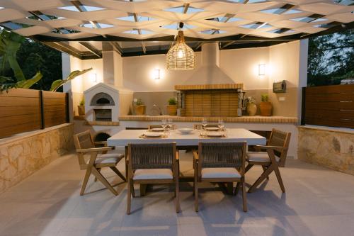 a patio with a table and chairs and a fireplace at Emerald Harmony Villa with Private Pool & Jacuzzi in Skouloúfia