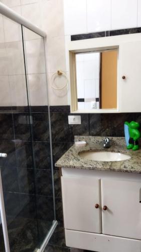 a bathroom with a shower and a sink and a mirror at Pousada Primavera in Caraguatatuba