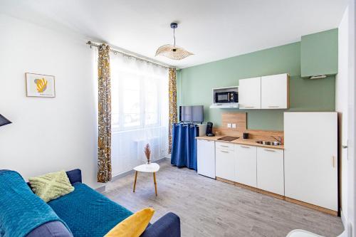 un salon avec un canapé bleu et une cuisine dans l'établissement Le Sauge d'Auch 