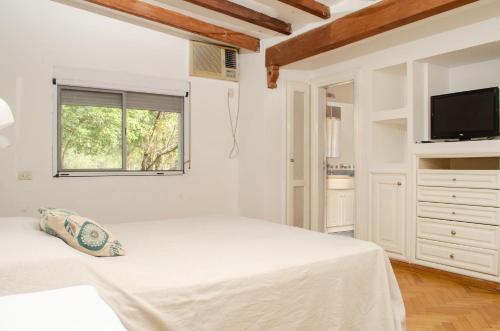 ein weißes Schlafzimmer mit einem Bett und einem Fernseher in der Unterkunft Casa de vacaciones con piscina y espacio recreativo in Santiago del Estero