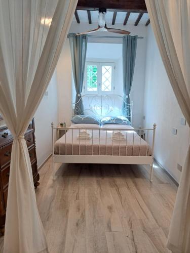 a bedroom with a bed with blue curtains and a window at Casina di Alice in Vinci