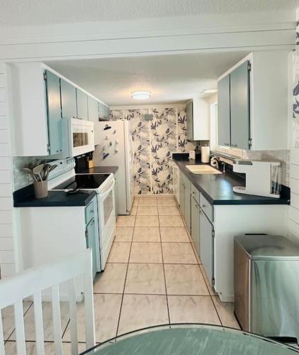 a kitchen with white appliances and a tile floor at Palme Bleu in Vero Beach