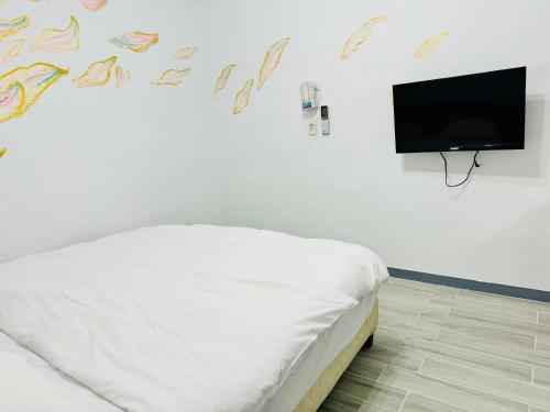 ein Schlafzimmer mit einem Bett und einem Flachbildfernseher in der Unterkunft 民宿記 台南安平可包棟 in Tainan