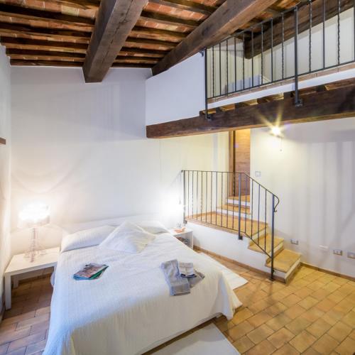 a bedroom with a white bed and a staircase at Agriturismo La Peonia in Bagnoregio
