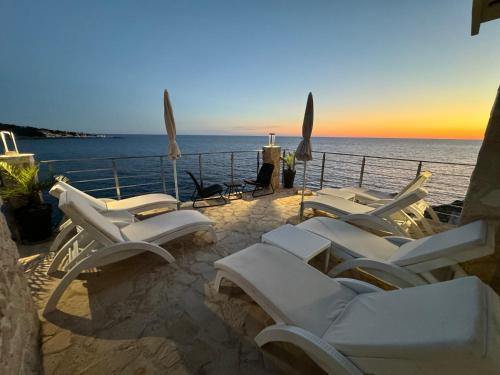 a group of white chairs sitting on a patio overlooking the ocean at Apart Lux Beciragic in Dobra Voda