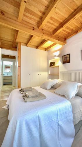 a large white bed in a room with wooden ceilings at The Cliffs - Casa Catuxa in Viveiro