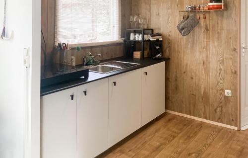 Una cocina con gabinetes blancos y un fregadero. en Pet Friendly StaCaravan, en Hattemerbroek