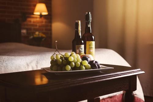 a tray of grapes and two bottles of wine on a table at Hotel Purkmistr in Plzeň