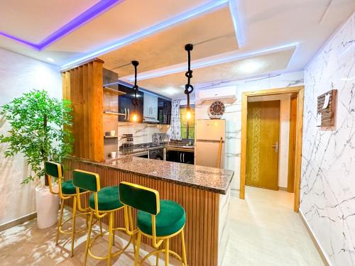 a kitchen with a bar with green stools at VELUXA - LUXURY HOLIDAY HOMES - Centric flat in Tangier