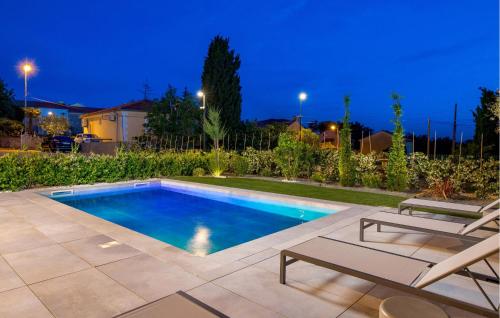 a swimming pool in a backyard with two lawn chairs at Beautiful Apartment In Omisalj in Omišalj