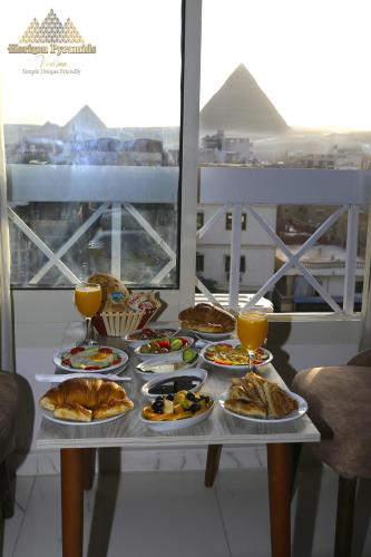 a table with plates of food and glasses of orange juice at Horizon Pyramids View inn in Cairo