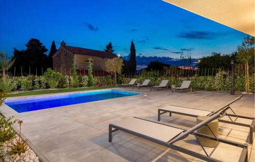 a swimming pool with lounge chairs in a backyard at Amazing Apartment In Omisalj in Omišalj