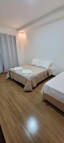 two beds in a room with wooden floors at Chalé Campo Florido in São Roque de Minas