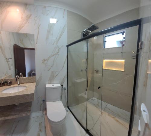 a bathroom with a shower and a toilet and a sink at Chalé Campo Florido in São Roque de Minas
