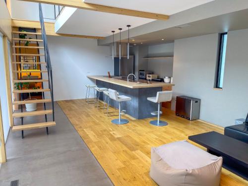 a kitchen and living room with a counter and a staircase at Mount Fuji view プライベートテニスコート付き高級リゾートヴィラ MAAA in Fujikawaguchiko