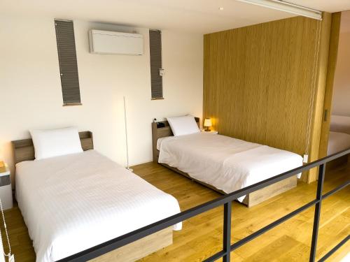 two beds in a room with white sheets at Mount Fuji view BBQ プライベートテニスコート付き高級リゾートヴィラ MAAA in Fujikawaguchiko