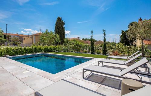 a swimming pool with two lounge chairs next to at Awesome Apartment In Omisalj in Omišalj