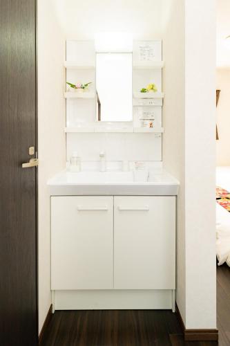 a white bathroom with a sink and a mirror at 44, Sumiyoshi 2, Entire house for rent, 住吉2 in Tokyo