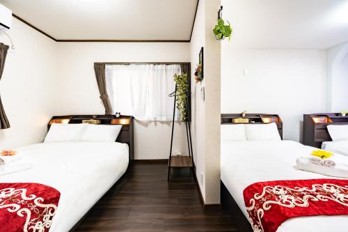 two beds in a room with white and red sheets at 44, Sumiyoshi 2, Entire house for rent, 住吉2 in Tokyo