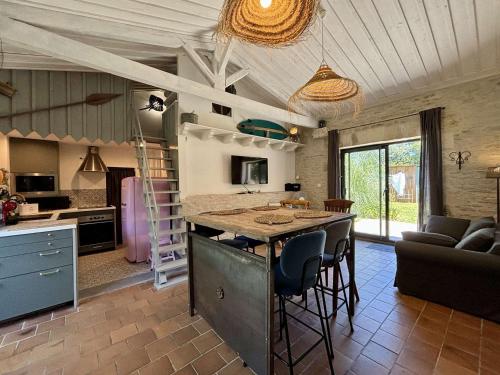 Il dispose d'une cuisine et d'un salon avec une grande île et des chaises. dans l'établissement Maison rénovée près de la plage, jardin privé et terrasse - 4 couchages - FR-1-246A-321, à Saint-Georges-dʼOléron