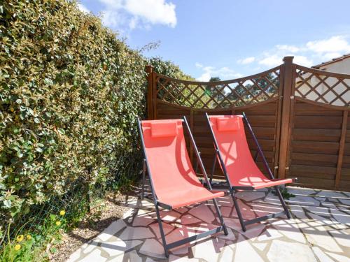 2 chaises assises sur une terrasse à côté d'une clôture dans l'établissement Maison avec piscine, tennis, proche plage et commerces à La Palmyre - FR-1-705-54, aux Mathes
