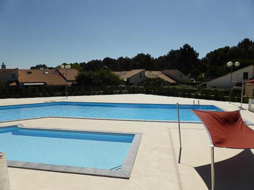 une grande piscine bleue avec un parasol rouge dans l'établissement Maison avec piscine, tennis, proche plage et commerces à La Palmyre - FR-1-705-54, aux Mathes