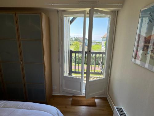 une chambre avec une porte ouverte sur un balcon dans l'établissement Cabourg: Bel appartement 3 pièces vue mer, 2 balcons, animaux admis - FR-1-487-370, à Cabourg