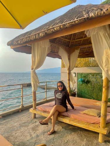 a woman sitting on a bed under an umbrella at The Philip Ann Resort in Mabini