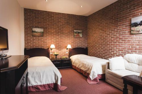 a hotel room with two beds and a brick wall at Hotel Purkmistr in Plzeň