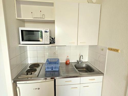 une petite cuisine avec un évier et un micro-ondes dans l'établissement Appartement 2 pièces avec piscine à 5 min de la plage de Pontaillac, parking résidentiel, balcon fermé - FR-1-550-81, à Vaux-sur-Mer